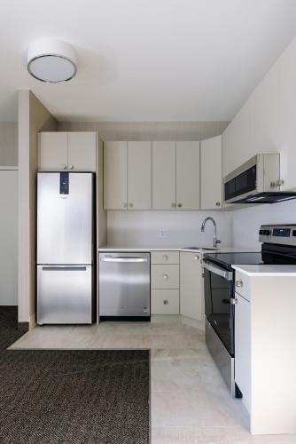 a kitchen with white cabinets and a stainless steel refrigerator at Balcomo, a Ramada by Wyndham in Penticton