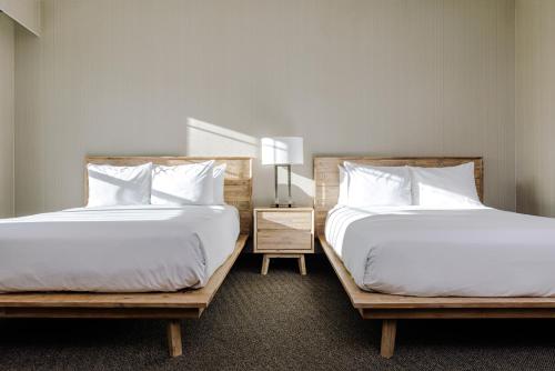 two beds sitting next to each other in a bedroom at Balcomo, a Ramada by Wyndham in Penticton