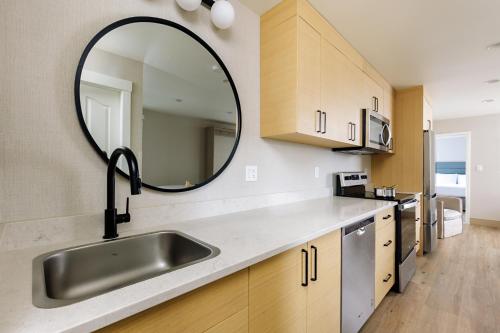 a kitchen with a sink and a mirror on the wall at Ramada by Wyndham Penticton Hotel & Suites in Penticton