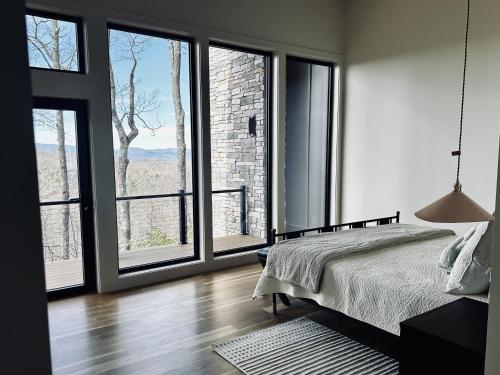 a bedroom with a bed and large windows at The Brevard Mountain Retreat New Construction with modern design, high-end furnishings & hot tub in Cedar Mountain