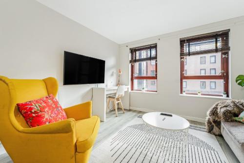 a living room with a yellow chair and a flat screen tv at The Merchants Gem - 2Bed & Free Parking in Glasgow