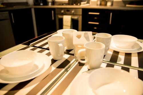 un mostrador con platos blancos y tazas. en Luxury Spacious Modern Apartment near city centre, en Mánchester