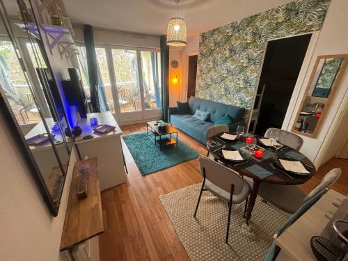 un salon avec une table et un canapé bleu dans l'établissement Splendide appartement 40m2 familial cabourg, à Cabourg