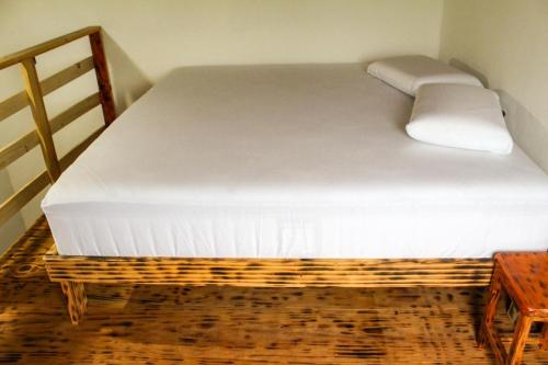 a large white bed in a room with a wooden table at Hostel Caraivando in Caraíva