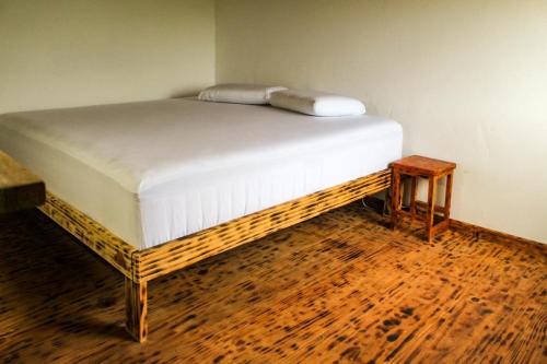 a bed in a room with a wooden floor at Hostel Caraivando in Caraíva