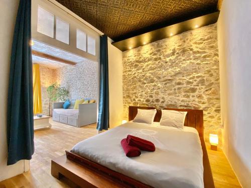 une chambre avec un lit et un mur en pierre dans l'établissement La Maison des Templiers ~ Ostal Médiéval ~ Logis enchantés, à Carcassonne