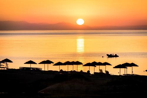 a beach with umbrellas and a boat in the water at Villa Maroula in Afantou