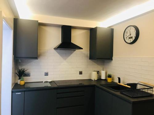 a kitchen with black cabinets and a clock on the wall at The Hideaway Thorpe Thewles in Thorpe Thewles