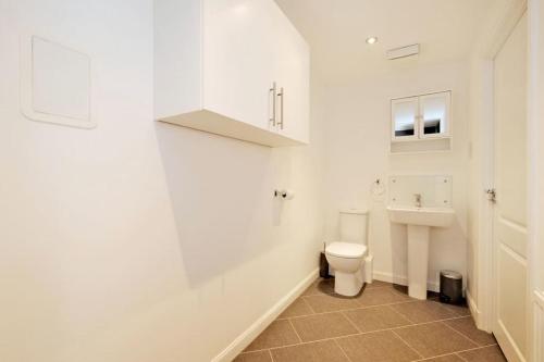 a white bathroom with a toilet and a sink at Ocean Apartments in Aberdeen