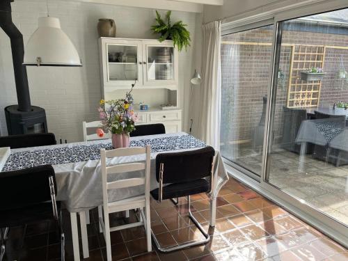 a dining room with a table with chairs and a window at Vakantiehuis Buitenplaats Schouwen in Burgh Haamstede