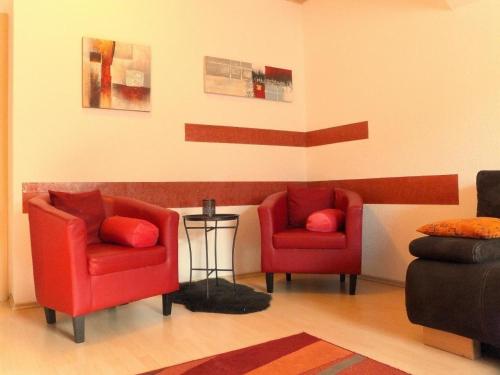 KreischaにあるFerienwohnung Sobrigauのリビングルーム(赤い椅子2脚、テーブル付)