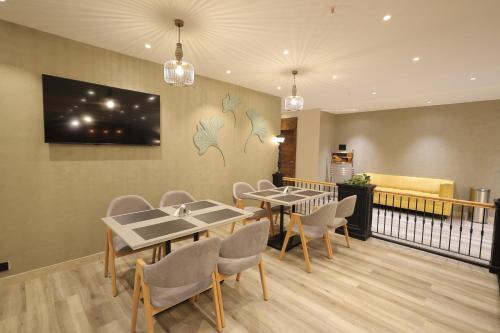 a dining room with tables and chairs and a tv on the wall at Aurum Keys By VYDA in Bengaluru