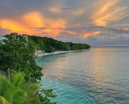 an island in the water with a sunset at Coralita Apartments in Saint Michael