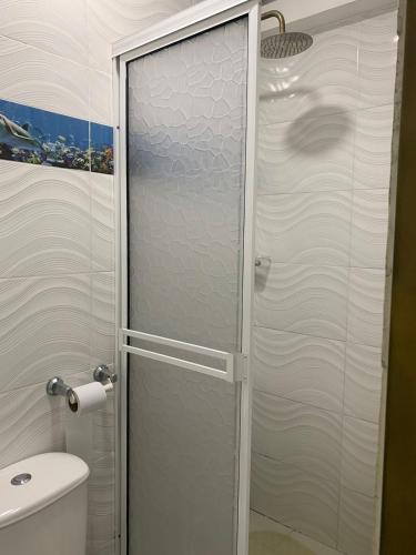 a glass shower door in a bathroom with a toilet at Hotel Oiba Alfa Plaza in Oiba