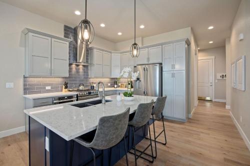 una cucina con armadi bianchi e un'isola con sgabelli da bar di NEW! Elegant Home near TPC Golf Course & Trails a Loveland