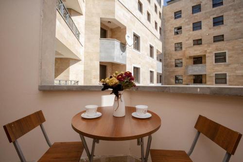 a table with two chairs and a vase with flowers at Apartment near Republic Square in Yerevan