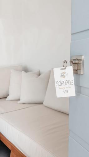 una cama con almohadas blancas y un cartel en ella en SOHOROS suites, en Schinoussa
