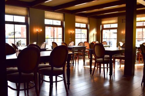 een eetkamer met tafels, stoelen en ramen bij Hotel Restaurant 't Ronde Loegh in Winschoten