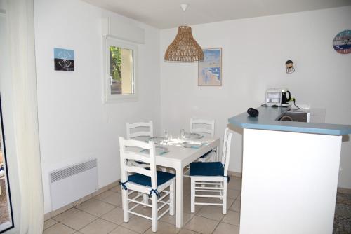 une petite cuisine avec une table et des chaises blanches dans l'établissement Maison avec 3 chambres et piscine proche de la plage, à Soulac-sur-Mer