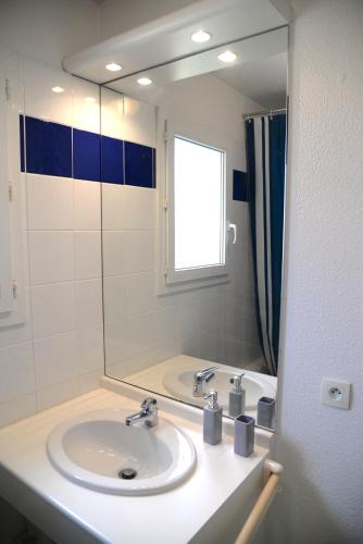 une salle de bain avec un lavabo et un grand miroir dans l'établissement Maison avec 3 chambres et piscine proche de la plage, à Soulac-sur-Mer
