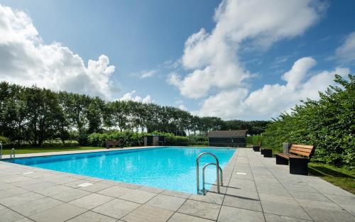 een zwembad met banken en een blauwe lucht bij Vakantiehuis Buitenplaats Schouwen in Burgh Haamstede