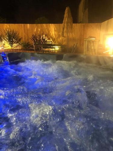 un bain à remous rempli d'eau bleue la nuit dans l'établissement L'étincelle, à Saint-Martin-des-Entrées