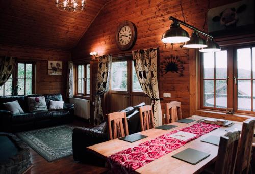 a dining room with a table and a clock on the wall at Bothy Cabin -Log cabin in wales - with hot tub in Newtown