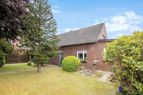 a brick house with a tree in the yard at Schöne Ferienwohnung in Berum mit Garten in Berumbur
