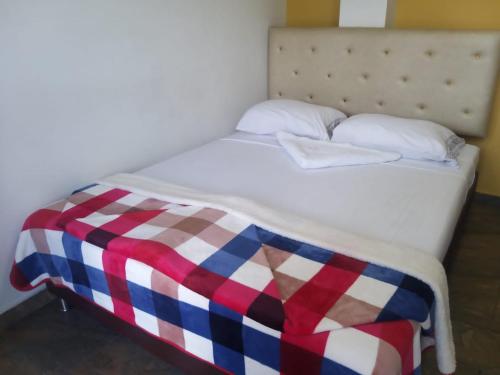 a bed with a red white and blue checkered blanket at Hotel Oiba Alfa Plaza in Oiba
