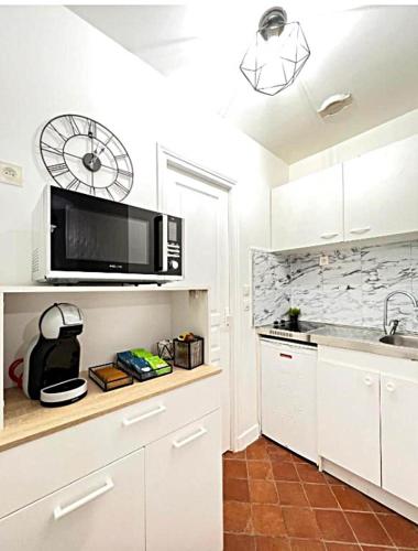 une cuisine avec des armoires blanches et un micro-ondes dans l'établissement Cocon Versaillais, à Versailles