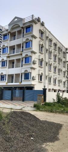 duży biały apartamentowiec z niebieskimi oknami w obiekcie Hotel Reliance w mieście kolkata