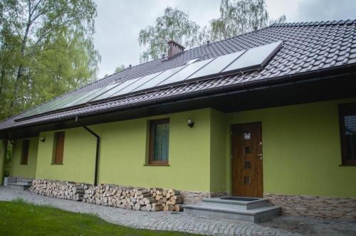 une maison verte avec des panneaux solaires sur le toit dans l'établissement Wohnung in Zieleniewo mit Garten und Grill, à Zieleniewo