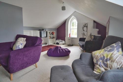 a living room with purple furniture in a attic at Roselyn House in Par