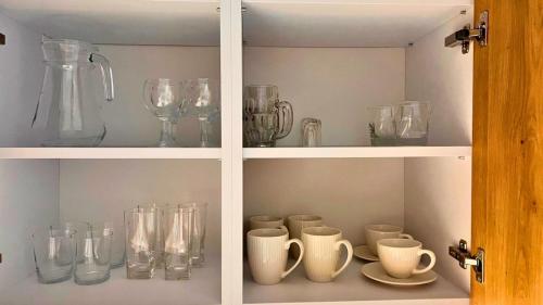 a cabinet filled with glass vases and other glass items at Apartament PURPLE in Poznań