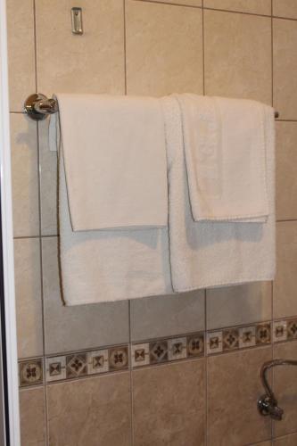 two white towels are hanging on a shower curtain at Motel Alas in Banja Luka