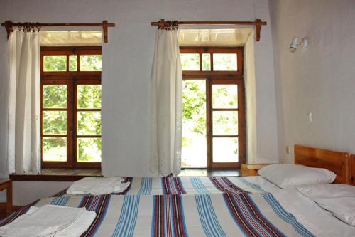 1 dormitorio con 2 camas y 2 ventanas en Sotos pension, en Skopelos Town
