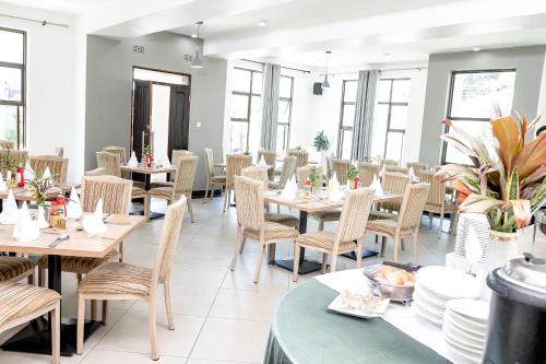 un restaurante con mesas y sillas de madera y ventanas en The Forty Four Hotel, en Lilongwe