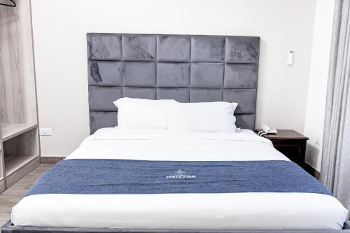 1 dormitorio con 1 cama grande y cabecero gris en The Forty Four Hotel, en Lilongwe