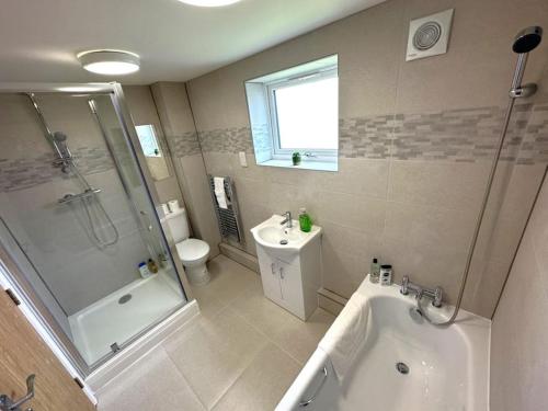 a bathroom with a tub and a shower and a sink at Elegant 2-Bed in Central Headington-Modern New Built Retreat- Wi-Fi, Netflix, Top Location in Oxford