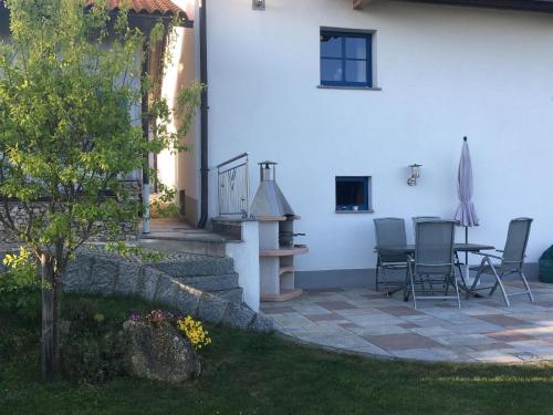 a patio with chairs and a table next to a building at Ferienwohnung für 2 Personen im Bayerischen Wald in Neureichenau