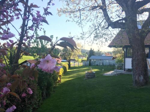 a garden with pink flowers and a tree at Ferienwohnung für 2 Personen im Bayerischen Wald in Neureichenau