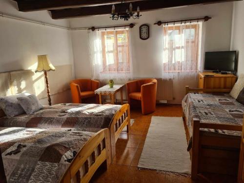 1 Schlafzimmer mit 2 Betten, einem TV und Stühlen in der Unterkunft GERENDÁS VENDÉGHÁZ in Mátraderecske