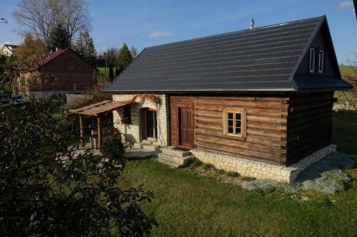 a small log cabin with a black roof at Ferienhaus in Cisowa mit gemeinschaftlichem Pool, Garten und Grill und Panoramablick in Cisowa