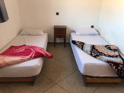 een kamer met 2 bedden en een nachtkastje bij Oceana surf house in Imsouane