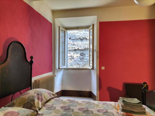 um quarto com paredes vermelhas e uma cama com uma janela em Il cortile di zia em Cagli