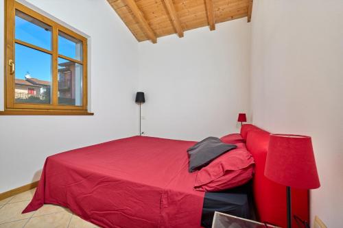a red bed in a white room with a window at A Casa di Anna Maria in Brenzone sul Garda