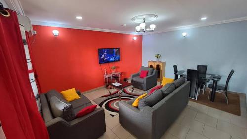 a living room with two couches and a red wall at Chimène appart in Kribi