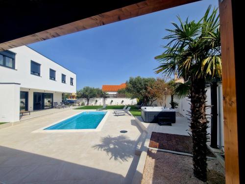 een huis met een palmboom naast een zwembad bij Villa Lumino in Murter