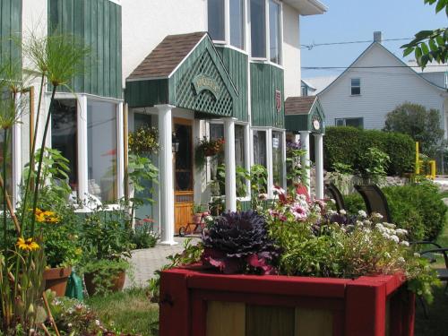 a house with a bunch of flowers in the yard at Hotel Le Pionnier in Tadoussac
