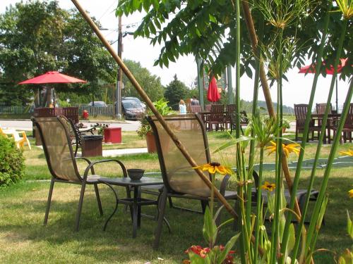 a couple of chairs and a table in the grass at Hotel Le Pionnier in Tadoussac